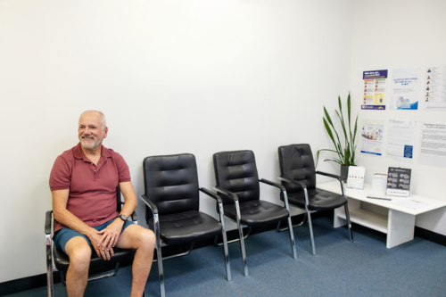 Senior man sitting patiently on chair in the waiting area - Australian Stock Image