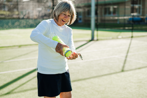 Senior woman opening a can of new tennis balls - Australian Stock Image