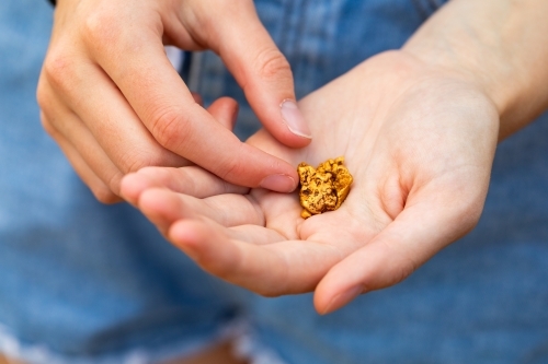 several small gold nuggets held in the hands of a girl - Australian Stock Image