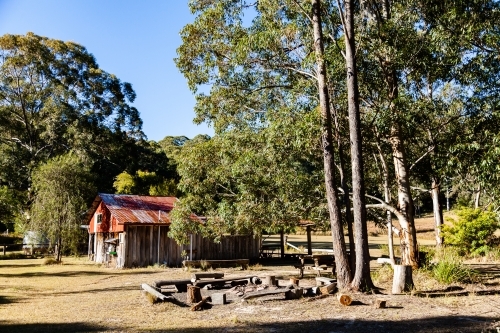 Shed and picnic area at campsite with campfire and seats