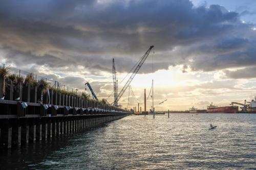 ship loading dock and cranes with sun shining through clouds - Australian Stock Image