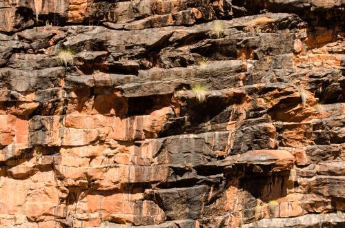 Shot of rocky cliff face with layered orange and dark rock