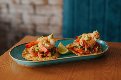 Shrimp Tacos Served on a Blue Plate With Lime Garnish in a Cosy Restaurant Setting - Australian Stock Image