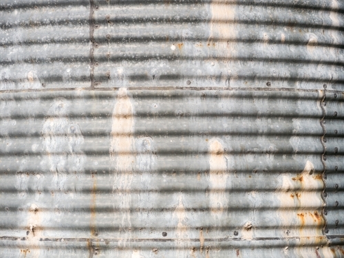 Side of an old, leaky corrugated iron water tank