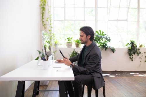 Side view of a man working in a minimal creative warehouse studio - Australian Stock Image