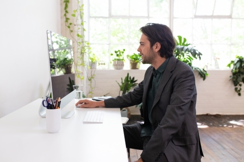 Side view of a man working on a computer in a creative studio - Australian Stock Image