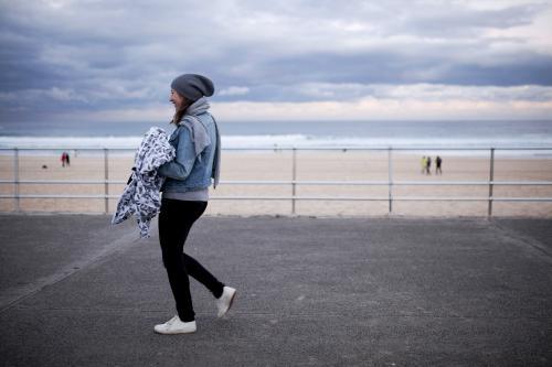 Side view of woman walking on the pavement by the beach
