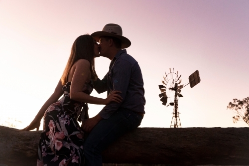 Side view show of a woman and a man with hat kissing under the purple and white sky - Australian Stock Image