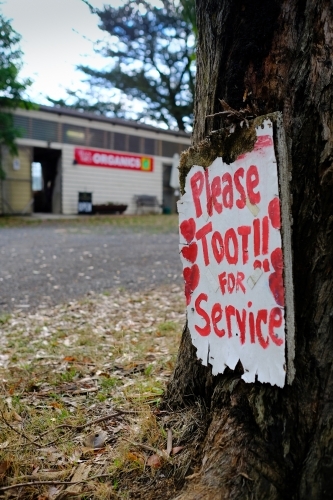 Sign saying "Please toot for service" placed on the foot of a tree