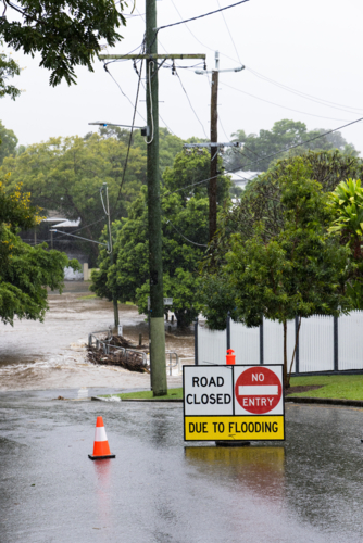 Signage across a flooded suburban road to stop traffic proceeding during a major rain event - Australian Stock Image