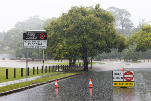 Signage on a road showing it is closed due to flooding in suburban Brisbane - Australian Stock Image