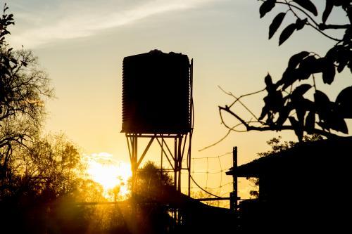 Silhouette of a rain water tank on a stand at sunset