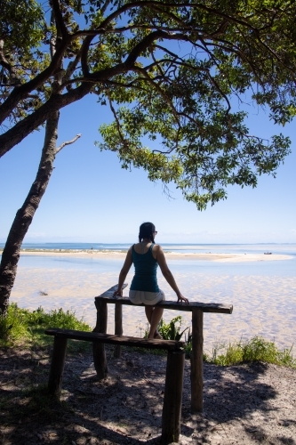 Silhouette of a woman sitting under a tree looking out towards Moreton Bay