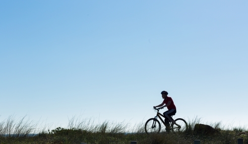 Silhouette of boy riding a bike - Australian Stock Image