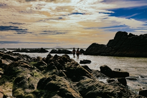 Silhouette of children swimming at The Tanks tourist attraction natural rock pool - Australian Stock Image