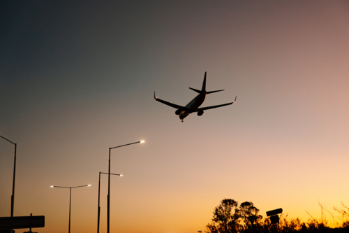 Silhouette of commercial airplane flying in the sky at sunset - Australian Stock Image