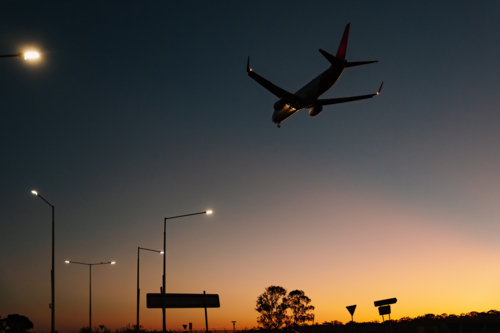 Silhouette of commercial airplane flying in the sky at sunset - Australian Stock Image