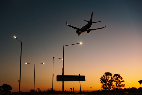 Silhouette of commercial airplane flying in the sky at sunset. - Australian Stock Image