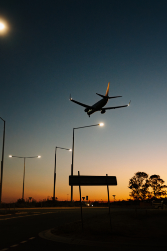 Silhouette of commercial airplane flying in the sky at sunset - Australian Stock Image
