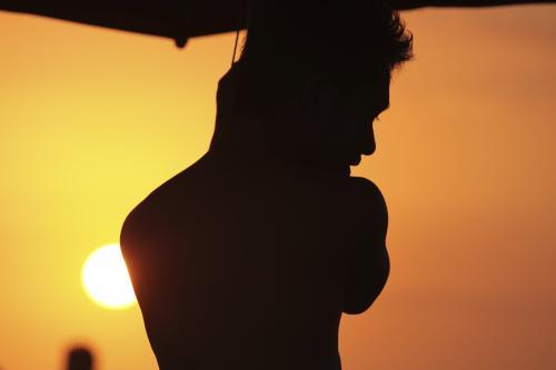 Silhouette of man against orange sky at beach - Australian Stock Image