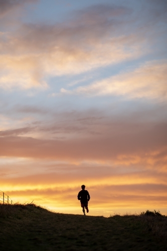 Silhouette of Man in Distance Running at Sunrise