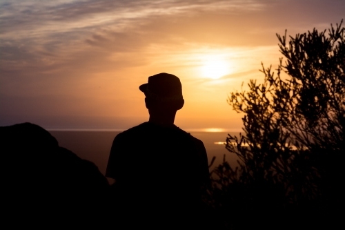 Silhouette of man looking out at sunrise