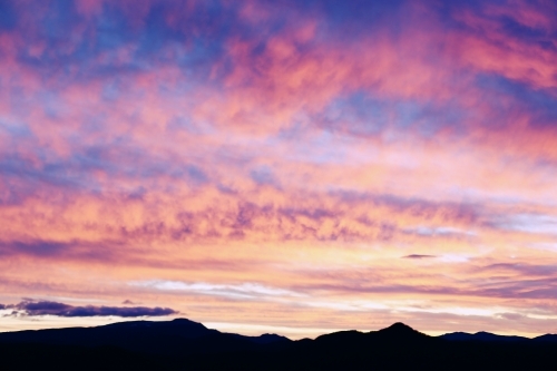 Silhouette of mountains under a dramatic sky at sunset.