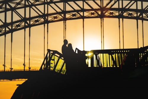 silhouette of people on a boat under Sydney Harbour Bridge - Australian Stock Image