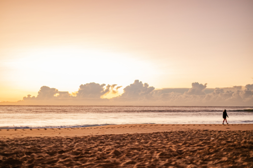 Silhouette of Person Walking on Beach at Sunset - Australian Stock Image