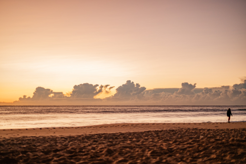 Silhouette of Person Walking on Beach at Sunset - Australian Stock Image
