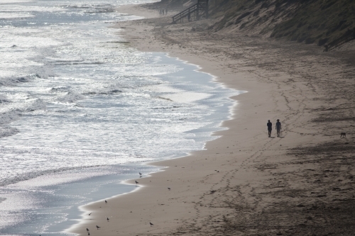 Silhouette of two distant people walking along a beach