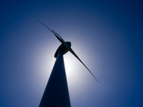 Silhouette of wind turbine against blue sky - Australian Stock Image