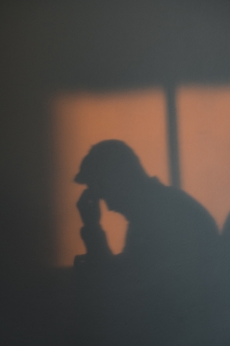 Silhouette shadow of a man with his head in his hands looking depressed
