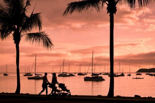 Silhouetted strollers with yachts in background at sunset on Airlie Beach.