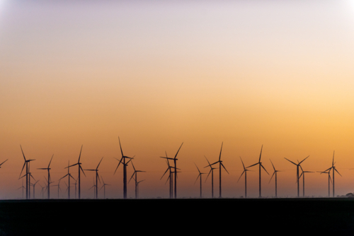 Silhouetted wind turbines at sunrise on a rural wind farm - Australian Stock Image