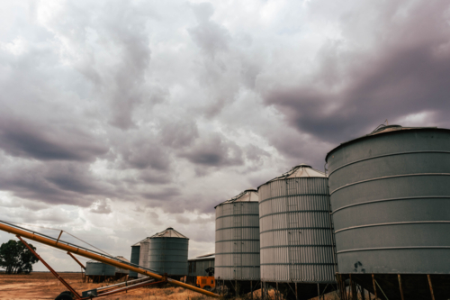 Silos standing in farm paddock as storm rolls in - Australian Stock Image