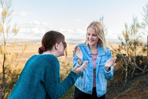 Sisters playing a clapping game laughing together - Australian Stock Image