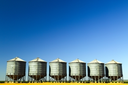 Six grain silos side by side on a farm near Breeza on the Liverpool Plains, New South Wales.
