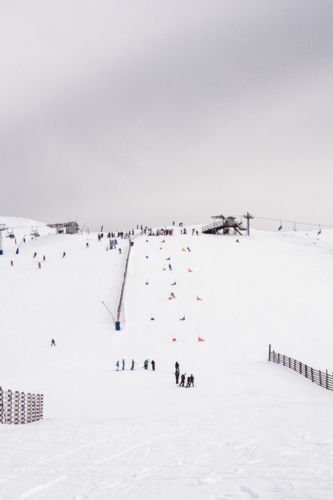 Ski lift with ski race course in distance on snowy mountain - Australian Stock Image