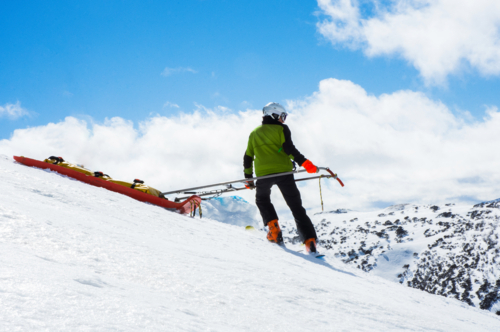 Ski rescue skiing down mountain with stretcher - Australian Stock Image