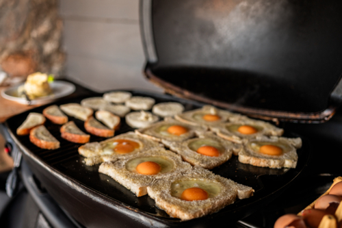 Slices of bread with eggs cooking on a barbecue grill in Crackenback - Australian Stock Image