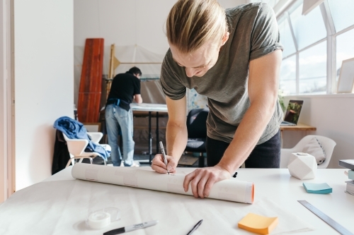 Small business employee packaging artwork to send in a tube - Australian Stock Image