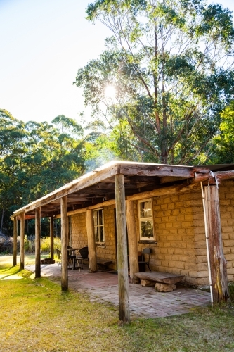 Small cabin with chimney and verandah in clearing - Australian Stock Image