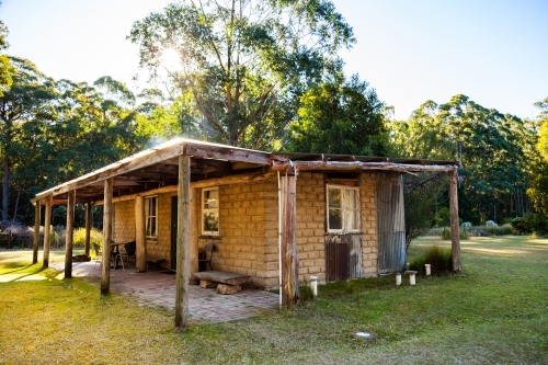 Small cabin with chimney and verandah in clearing - Australian Stock Image