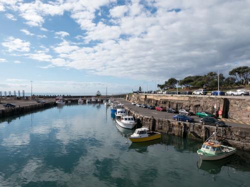 Small fishing boats in a harbour with reflected cloudy sky - Australian Stock Image