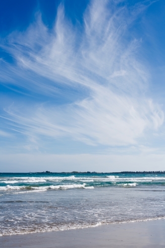 small waves breaking on a beach under a big sky