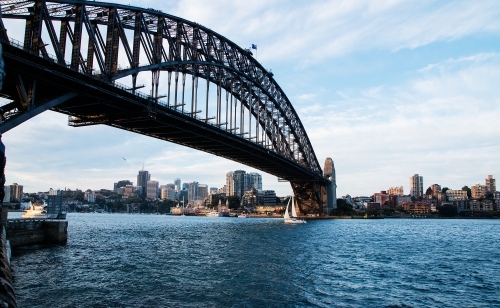 small yacht sailing under Sydney Harbour Bridge - Australian Stock Image