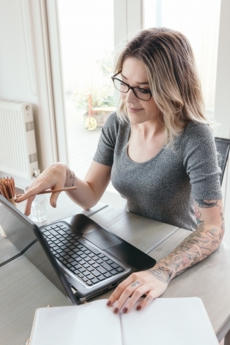 Smart young successful female working on a laptop at home - Australian Stock Image