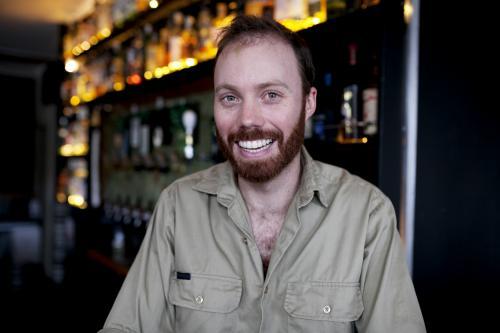 Smiling bartender behind the bar at local craft beer pub - Australian Stock Image