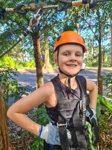 Smiling boy wearing safety gear during treetop adventure challenge - Australian Stock Image